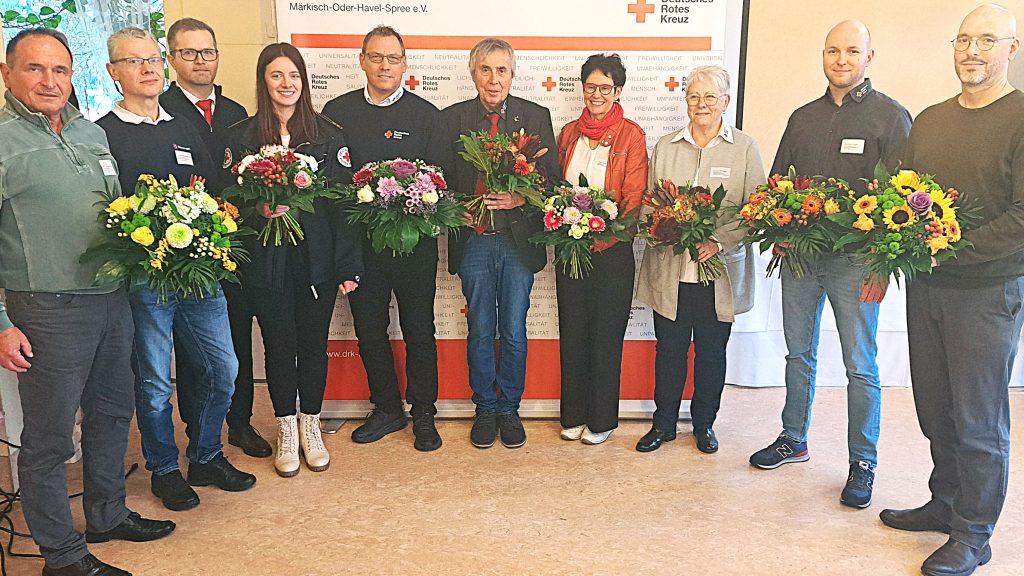 Die Mitglieder des neu gewählten Präsidiums des DRK-Kreisverband Märkisch-Oder.Havel-Spree stehen in einem Halbkreis und lächeln in die Kamera. In der Mitte steht der wiedergewählte Präsident Manfred Helbig.