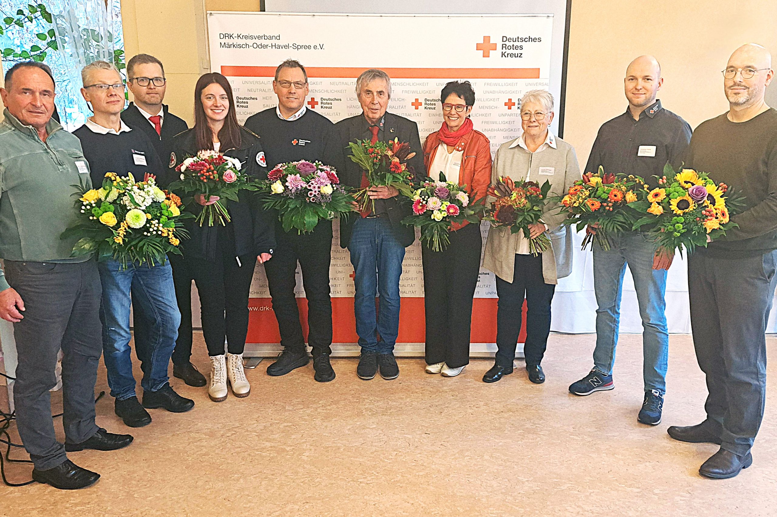 Die Mitglieder des neu gewählten Präsidiums des DRK-Kreisverband Märkisch-Oder.Havel-Spree stehen in einem Halbkreis und lächeln in die Kamera. In der Mitte steht der wiedergewählte Präsident Manfred Helbig.