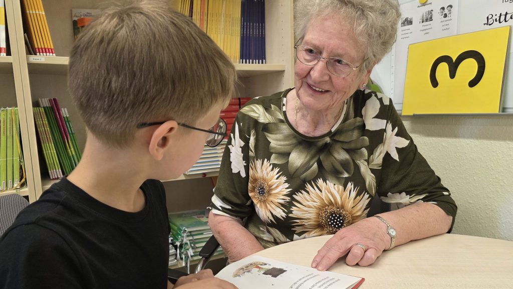 Ein Schüler aus der Margeriten-Schule liest Rosemarie Nützler-Bau aus dem Senior*innenwohnen in Borgsdorf vor.