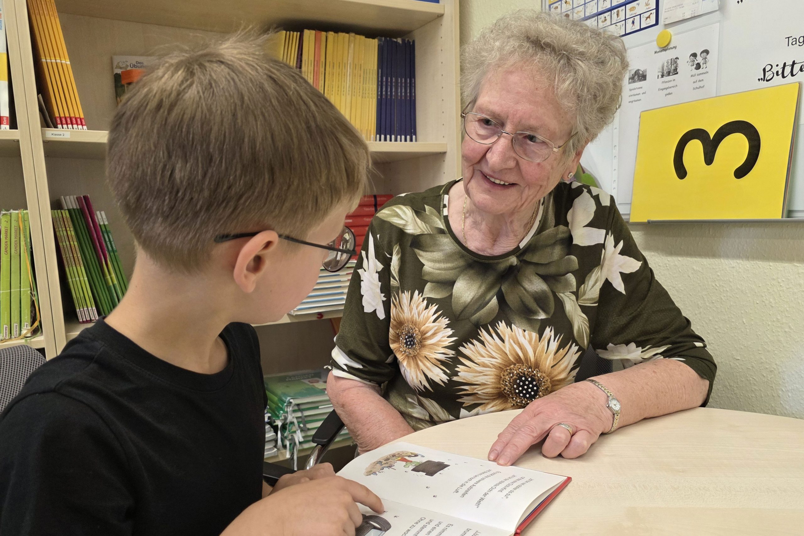 Ein Schüler aus der Margeriten-Schule liest Rosemarie Nützler-Bau aus dem Senior*innenwohnen in Borgsdorf vor.