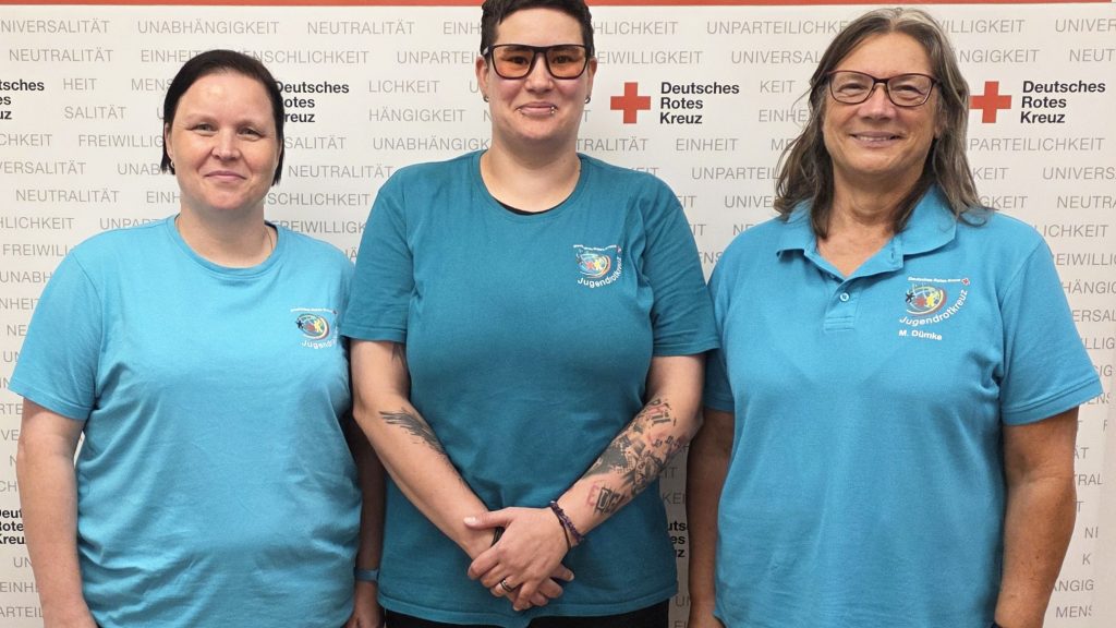 Drei Frauen mit Shirts des Jugendrotkreuz stehen nebeneinander und posieren für die Kamera.