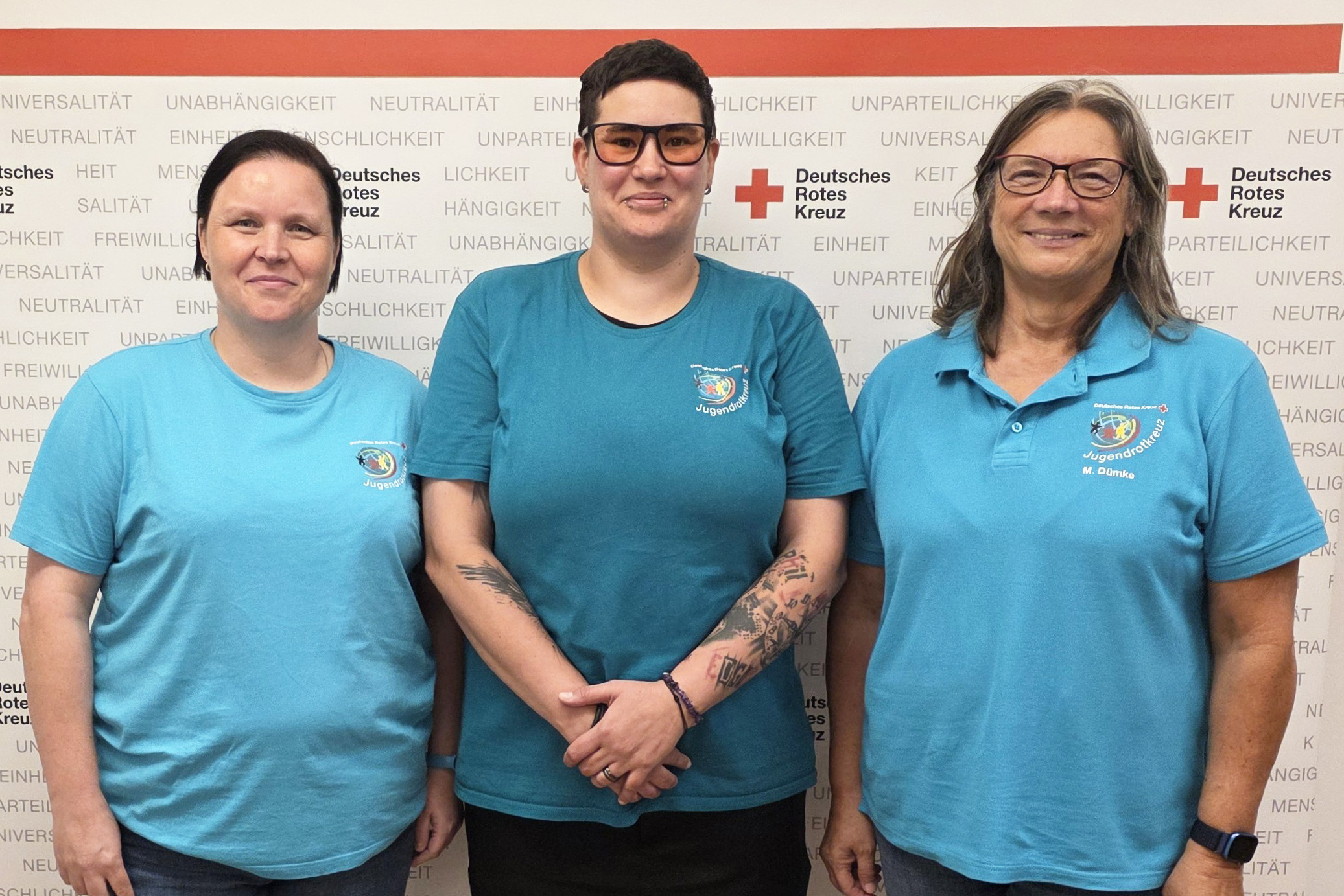 Drei Frauen mit Shirts des Jugendrotkreuz stehen nebeneinander und posieren für die Kamera.